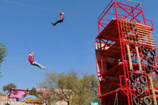 Ecoproparks. Personas usando tirolesas en torre de aventura.