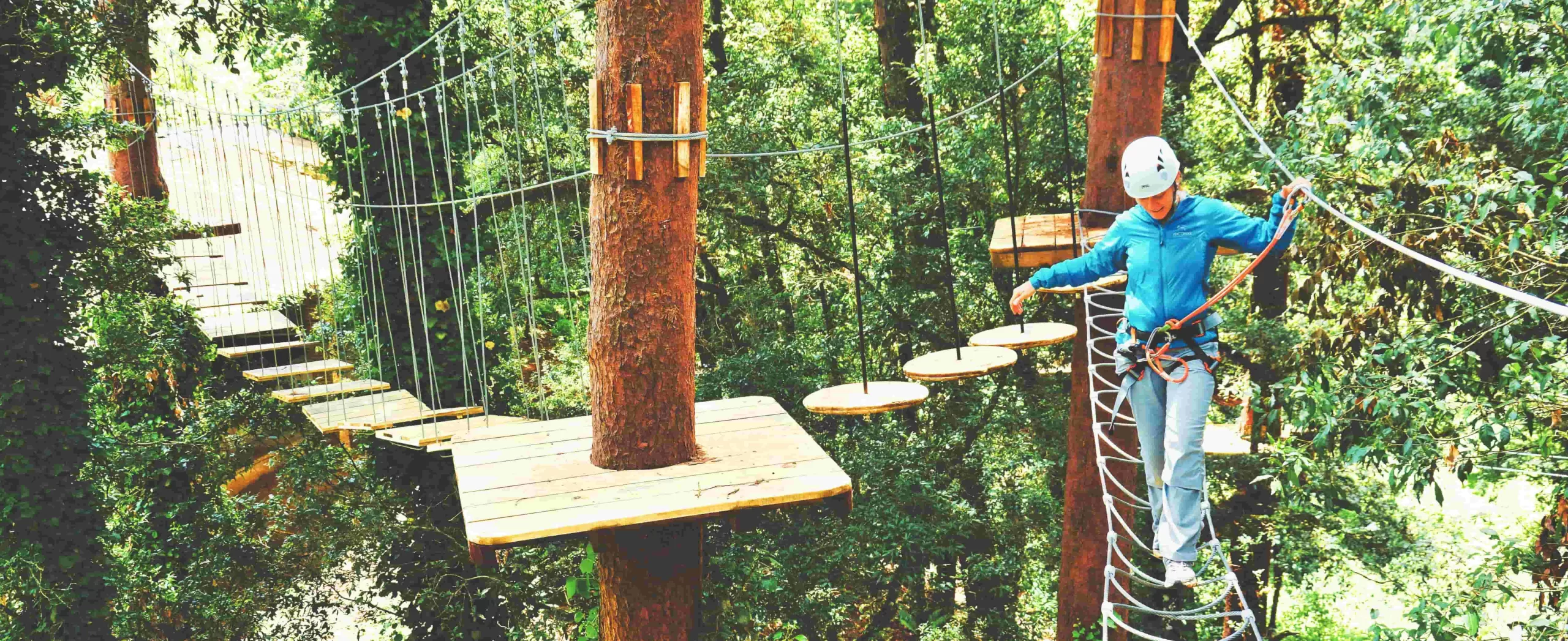 Ecoproparks. Persona caminando sobre una construcción de madera en un bosque, parte de los servicios que ofrece Ecoproparks.