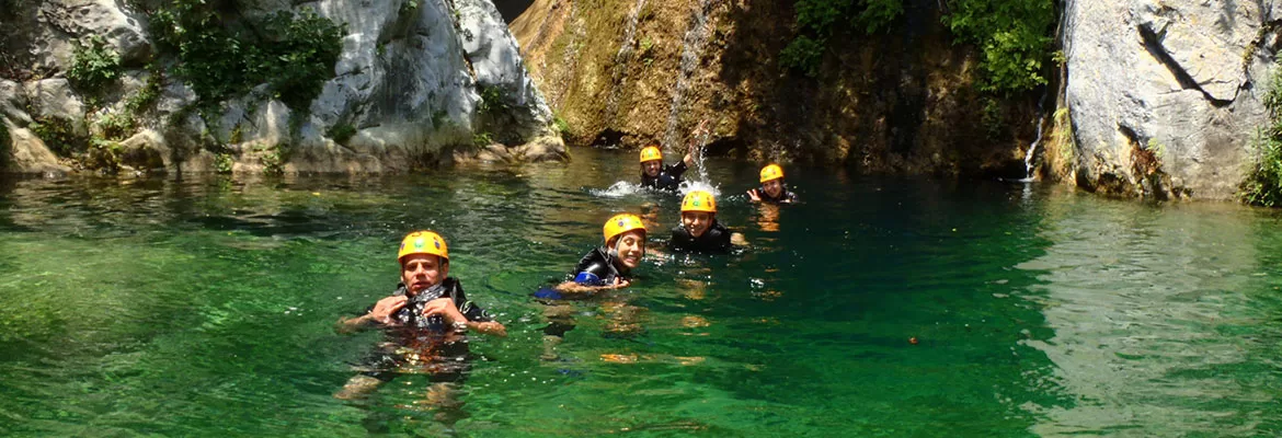 Ecoproparks. Personas nadando en río con rocas alrededor.